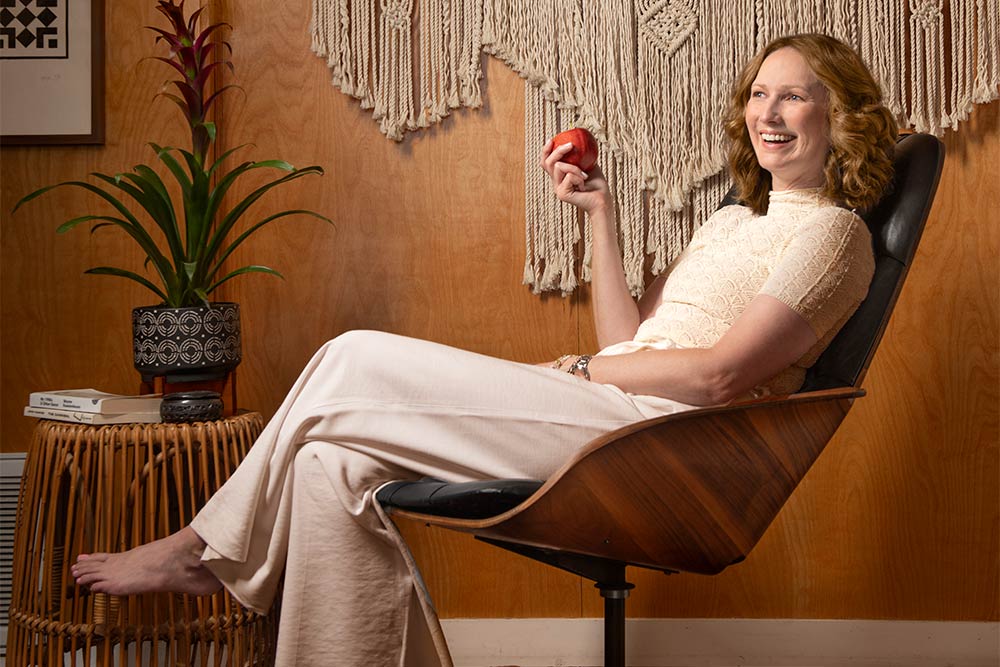 Lauren Yerkes sits in a reclining chair, holding a red apple